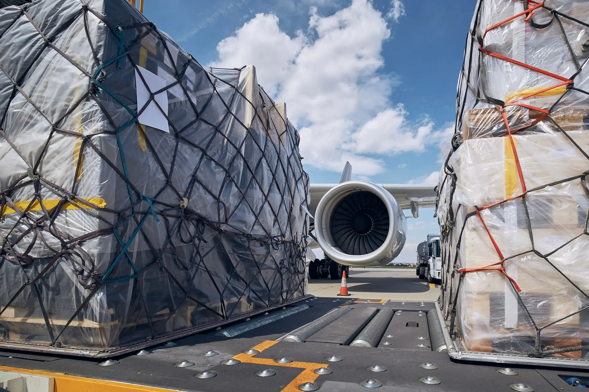 Netted air cargo pallets built up on the ramp beside a freighter aircraft, ready to be tendered to the airline