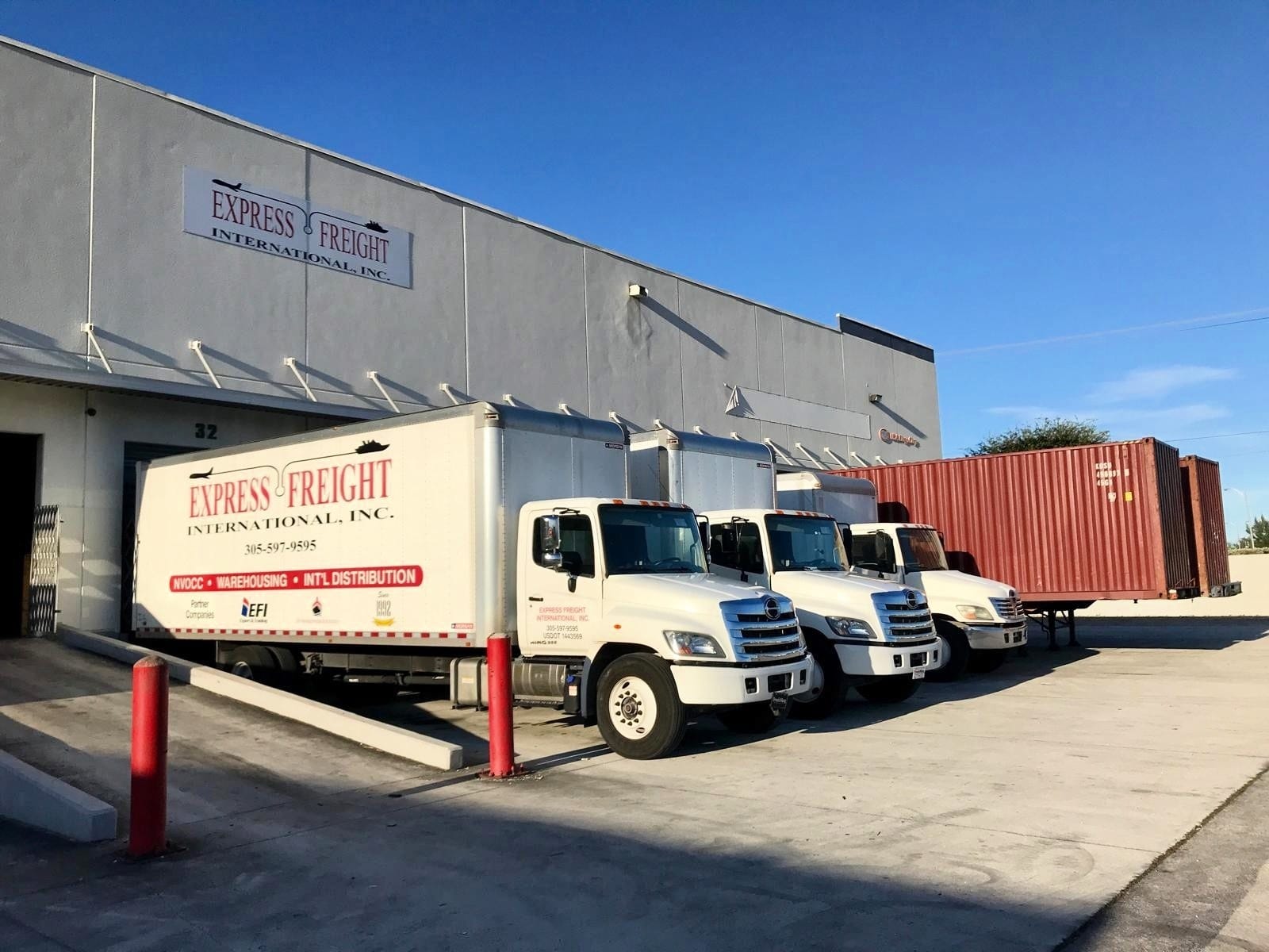 Three EFI box trucks at the dock doors of the Medley, Miami warehouse, under the company sign