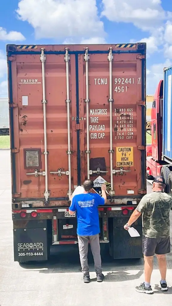 Workers inspecting a hazardous materials shipping container on truck