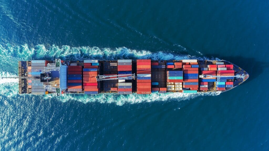 A loaded container ship under way on open water, seen from directly above
