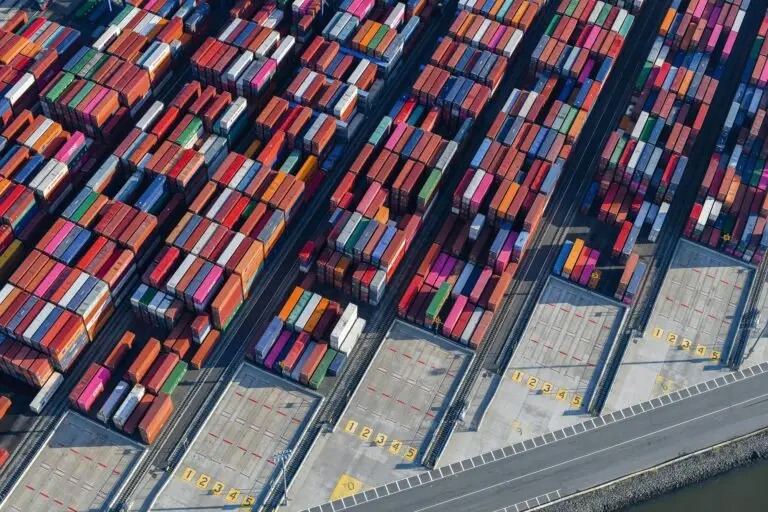 Filas de contenedores de muchos colores apilados en un patio, vistos desde arriba