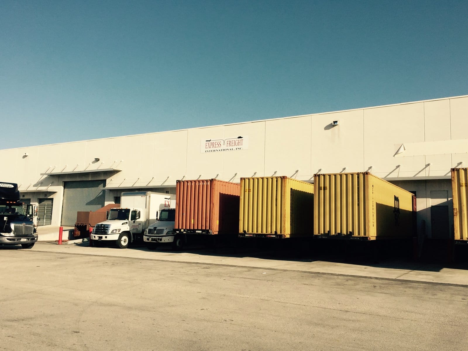 Express Freight International warehouse loading dock with shipping containers and trucks, Miami FL