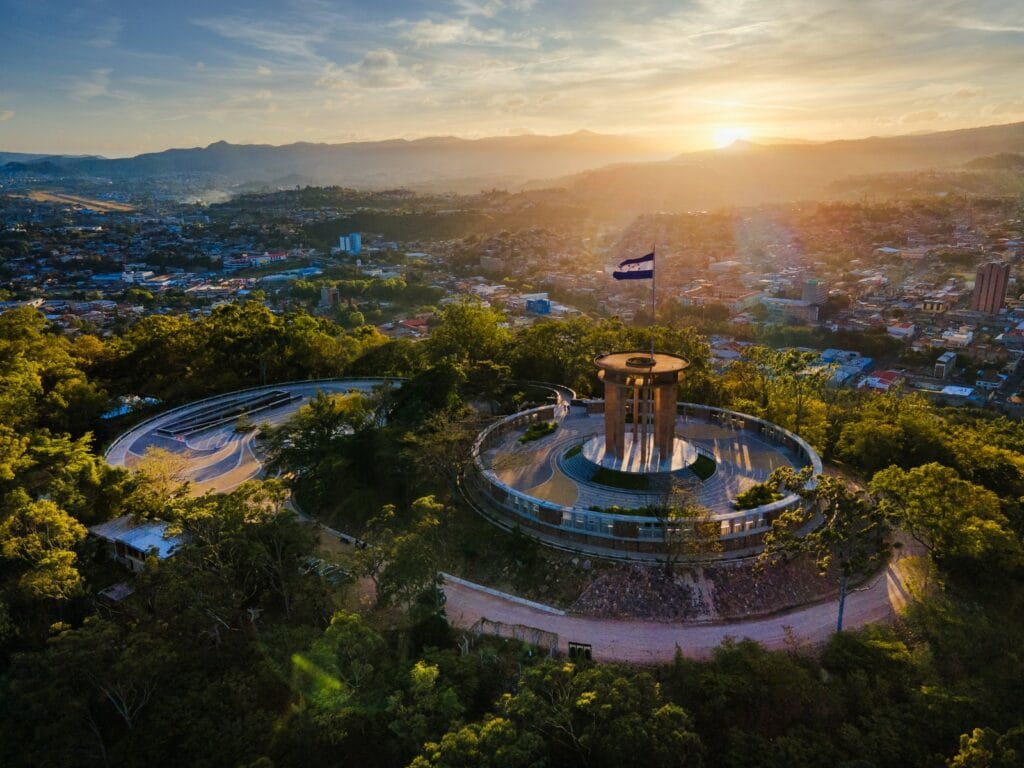 Tegucigalpa, Honduras, at sunset, with the national flag flying over a hilltop monument
