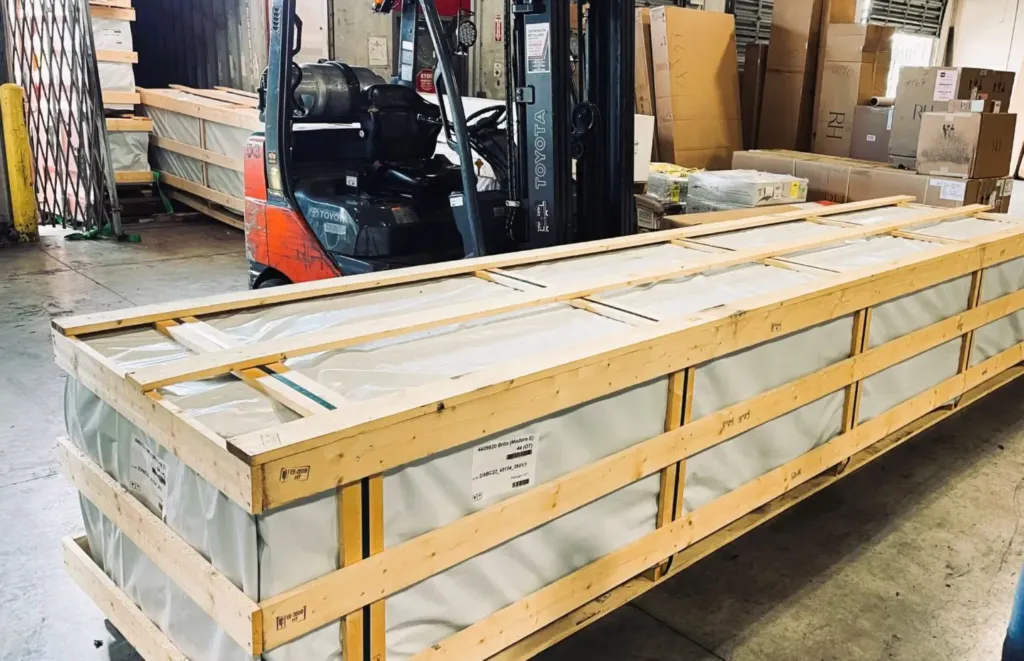 A long timber export crate built around its cargo on the warehouse floor.