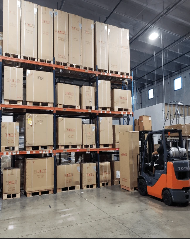Palletized cartons on warehouse racking, with a forklift in the aisle