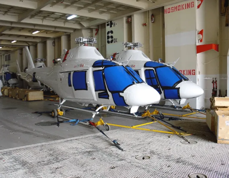 Two helicopters secured with tie-down straps, ready for shipment