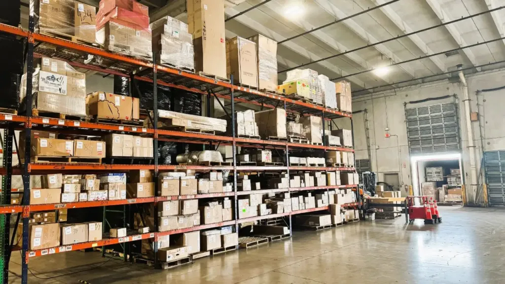 Warehouse floor with pallet racking and a worker moving freight near the receiving door