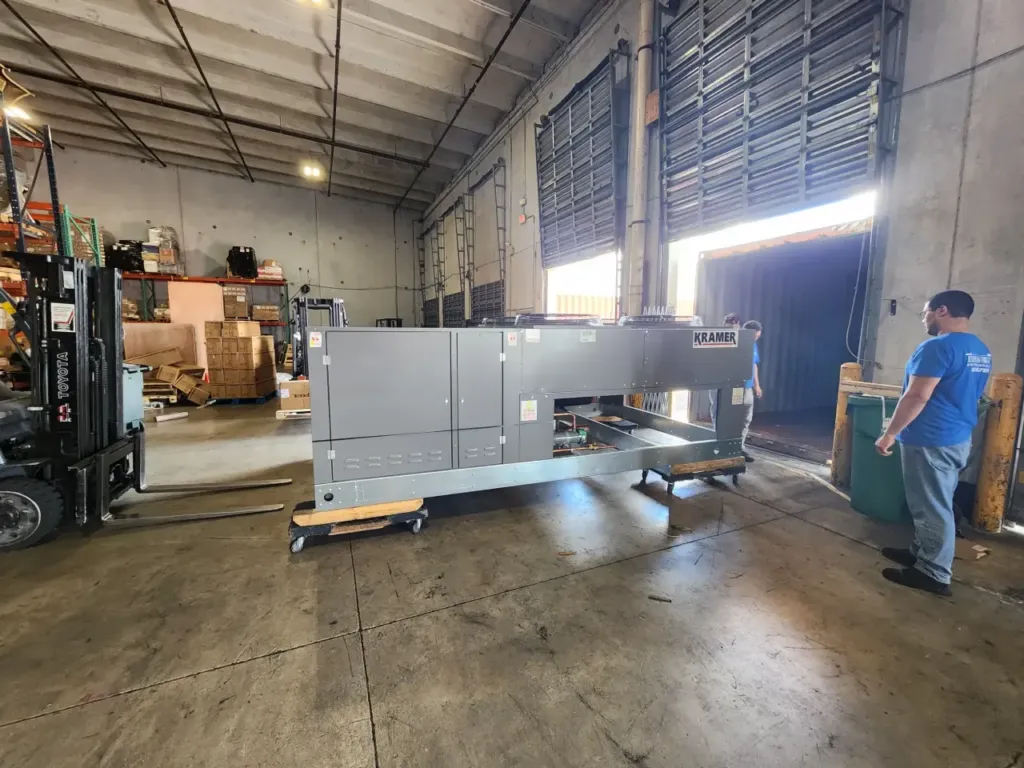 EFI crew guiding a large HVAC unit into a shipping container.