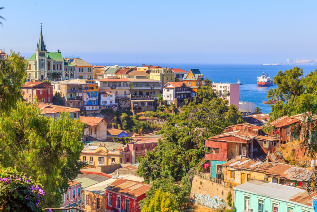 Painted houses on the hills of Valparaíso, Chile, with a cargo ship entering the bay