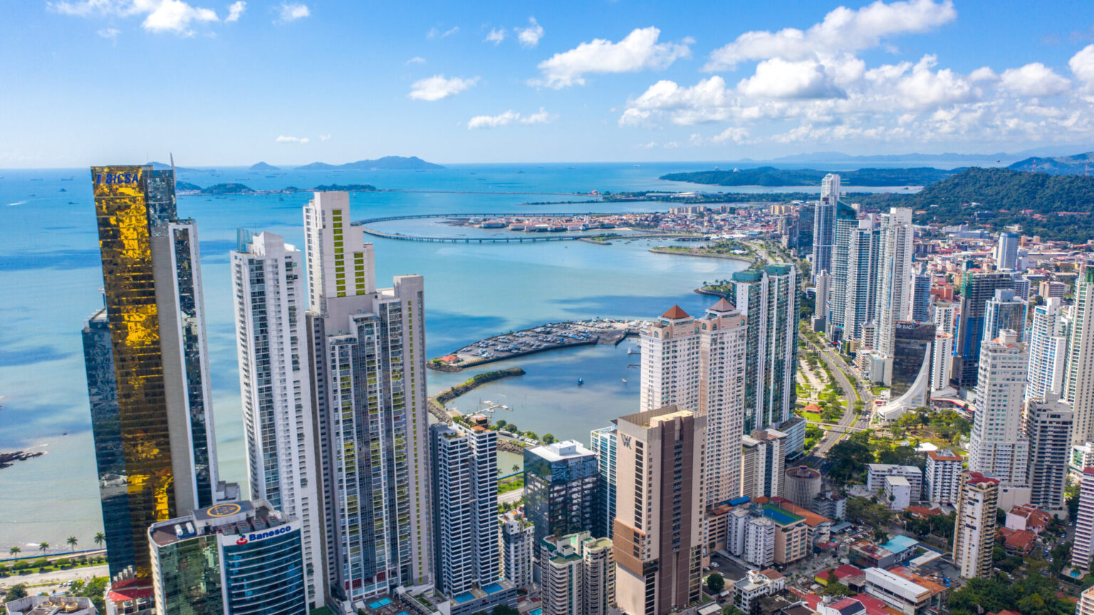 Aerial view of the Panama City skyline on the bay, with a coastal highway curving out over the water