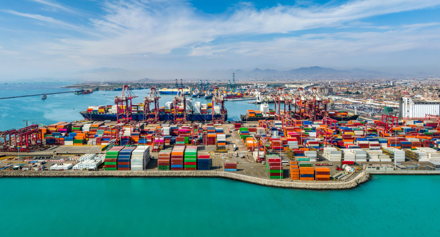 Aerial view of the port of Callao, with container cranes at work and the city and the Pacific beyond